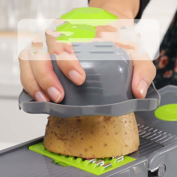 Person using a stainless steel vegetable cutter to slice a potato in a kitchen setting