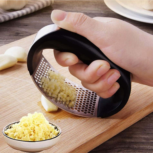 Stainless Steel Garlic Masher crushing garlic on a wooden board for effortless meal prep.