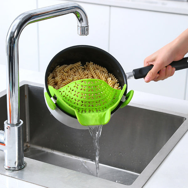 Silicone Pot Side Drain Stopper attached to pot, draining pasta in sink for safe kitchen use.