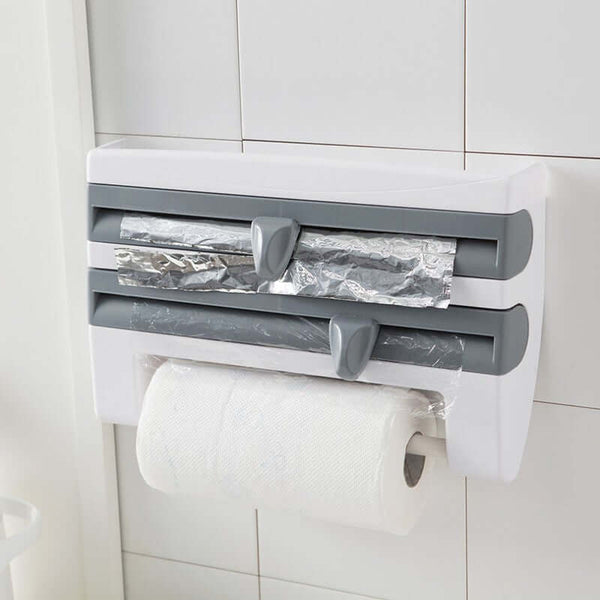 4-in-1 Kitchen Roll Holder Dispenser for foil, film, wrap, and tissue paper on a tiled wall, featuring a compact, space-saving design.