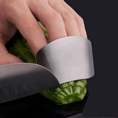 Stainless steel finger guard protecting fingers while slicing cucumber, ideal for safe kitchen tool use and cutting precision.