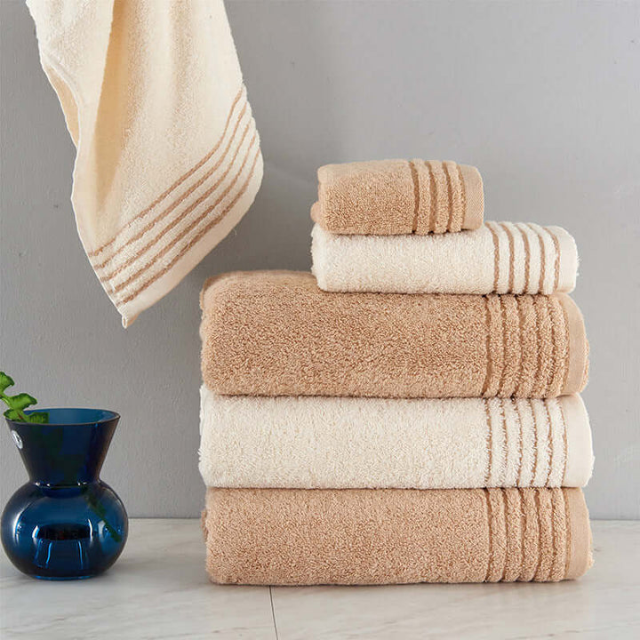 Soft cotton towel set in beige and white, neatly stacked, showcasing luxurious design for home use.