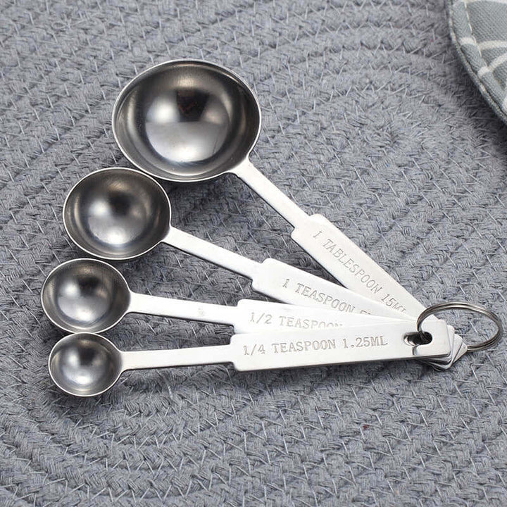 Stainless steel baking measuring spoon set on textured surface for precise cooking and baking measurements.