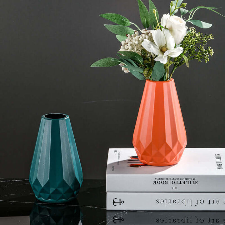 Nordic-style teal and orange vases with flowers, on a book, complementing Japandi decor and bold color palettes.