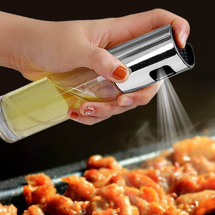 Person using a BBQ oil & vinegar spray bottle over grilled chicken, promoting healthy cooking and portion control.