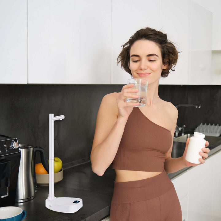 Person using an automatic water dispenser in a modern kitchen, highlighting easy water access and sleek biophilic design elements.