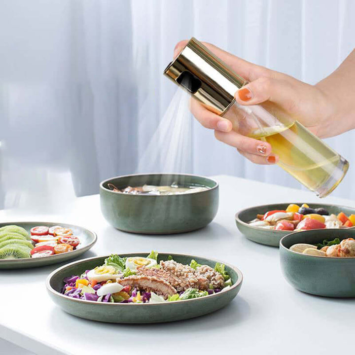 Hand using BBQ Oil & Vinegar Spray Bottle on salad, promoting healthy cooking with controlled oil application.