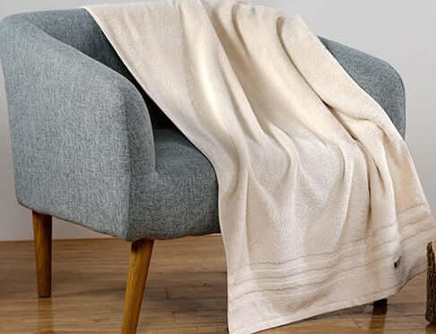 Luxurious soft cotton towel draped over a modern chair, embodying sustainable, cozy Japandi style with a biophilic design touch.