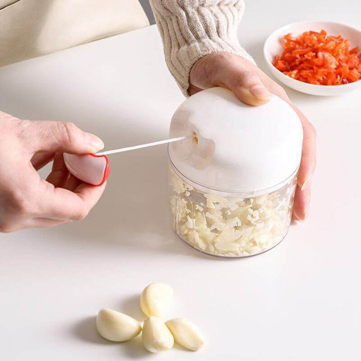 Small Cut-and-Pull Garlic Press with 300ML capacity for easy garlic prep, shown in use on a kitchen counter with garlic cloves nearby.