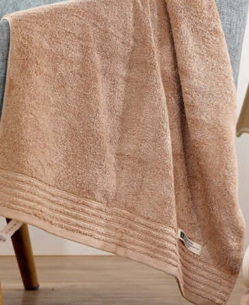 Luxurious soft cotton towel draped over chair, highlighting its absorbent texture and perfect for modern and cozy home decor.