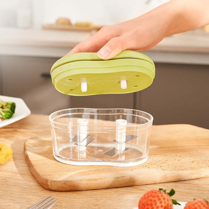 Hand Push Garlic Press in lime color, multifunctional kitchen gadget for easy garlic cutting on a wooden board.