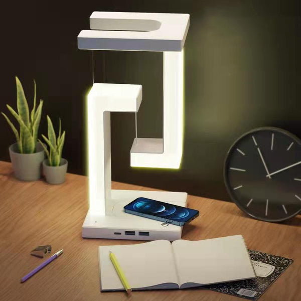 Creative Wireless Charging Suspension Table Lamp with floating design on a desk, featuring a smartphone charging base.