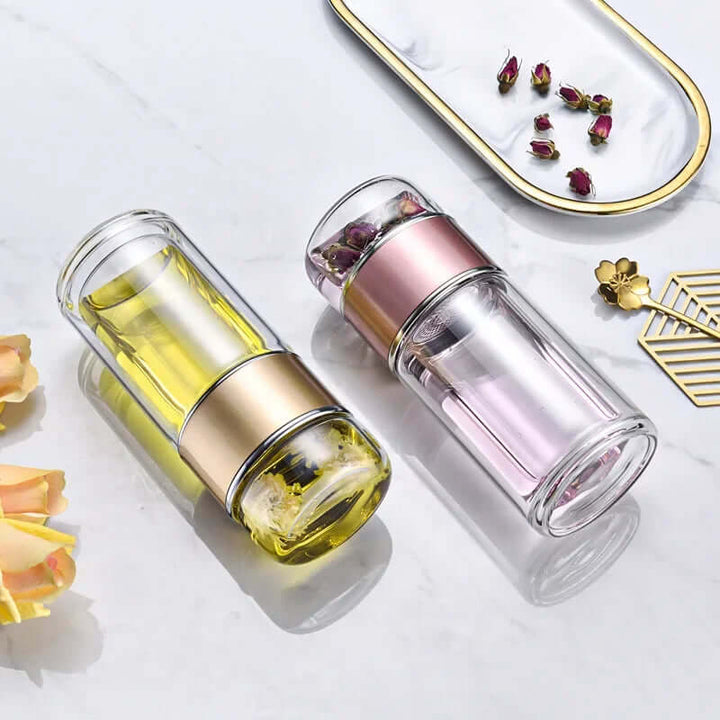 Glass tea infuser bottles with built-in stainless-steel filters, shown with floral decor, ideal for modern home and travel use.