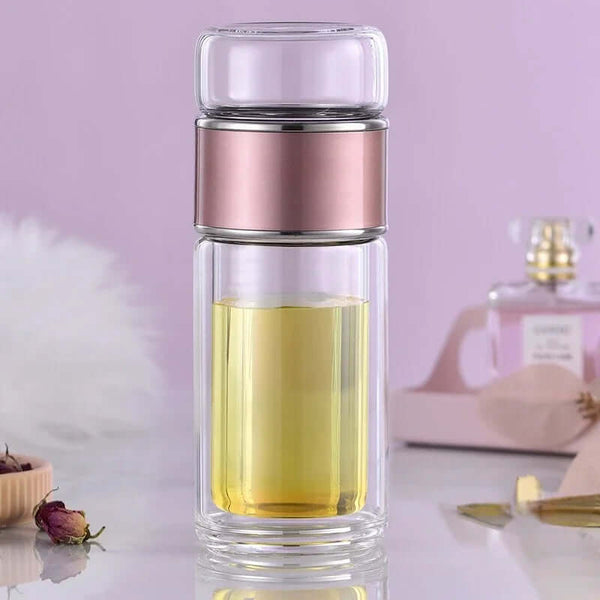 Tea Infuser Bottle made of durable glass with built-in stainless steel filter, shown on a modern table with home decor accents.